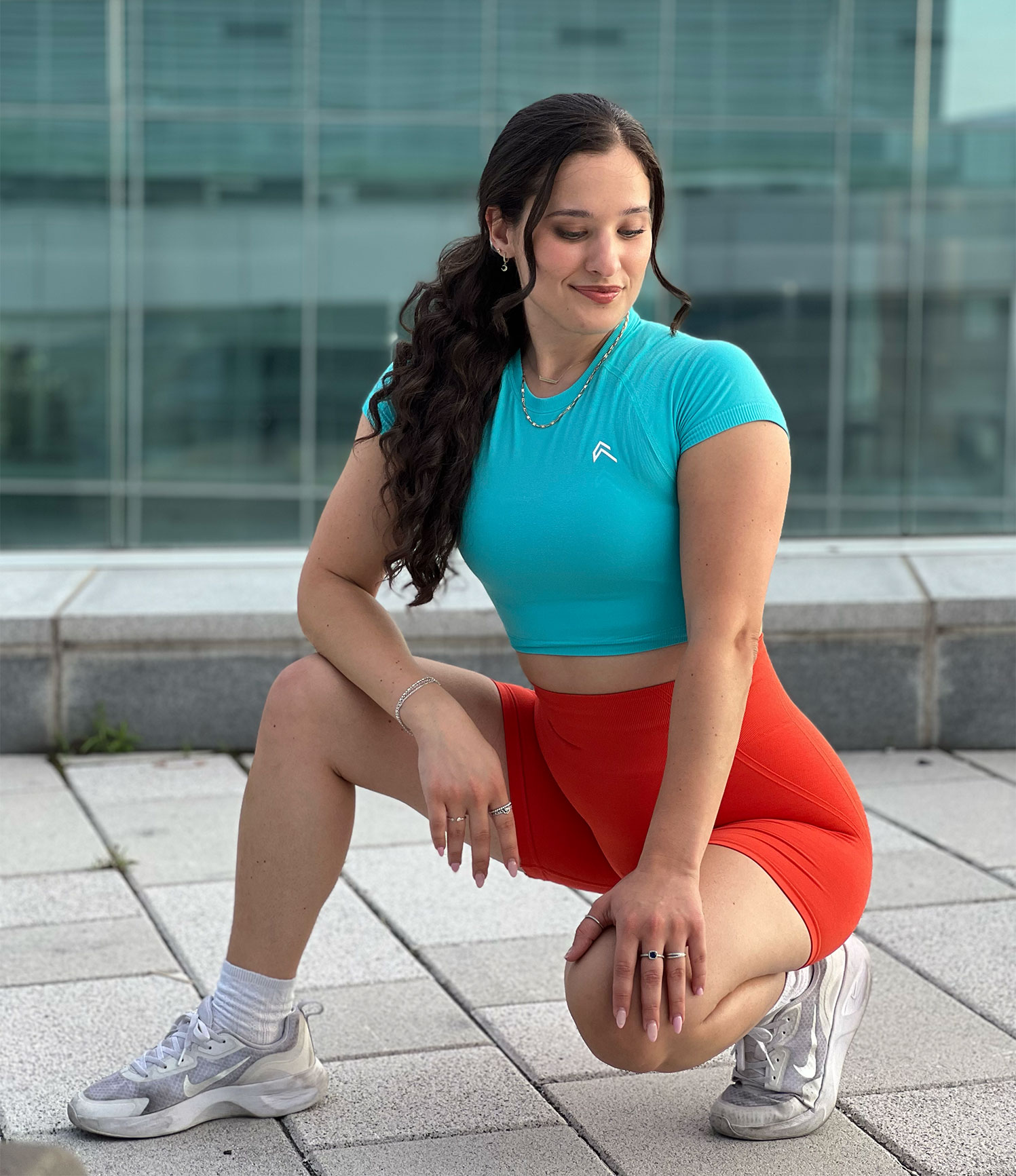 Coach kneeling outside, wearing fitness clothes